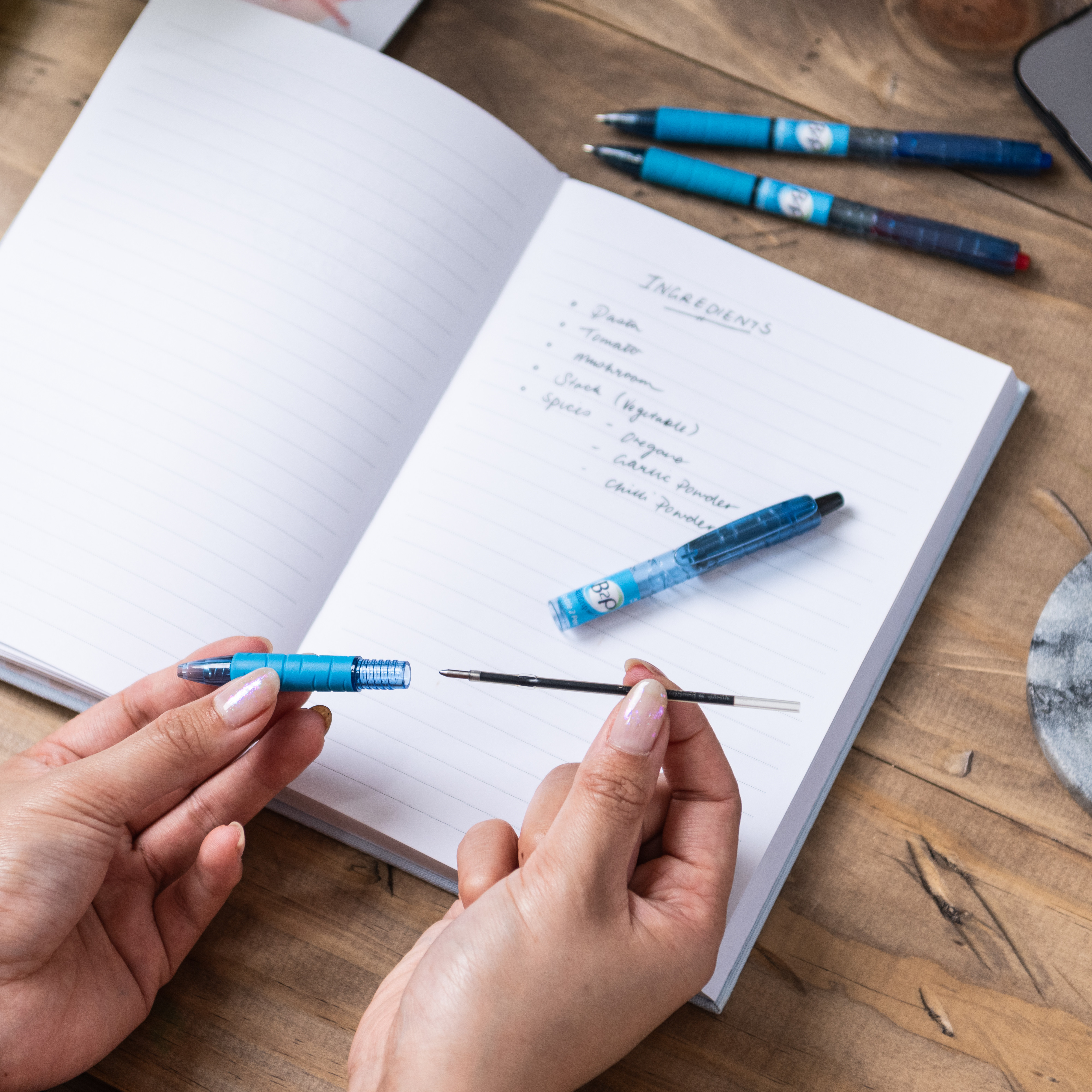 Close-up view of a person refilling a BeGreeN B2P (Bottle to Pen) recycled plastic pen, highlighting the sustainability aspect of the product.