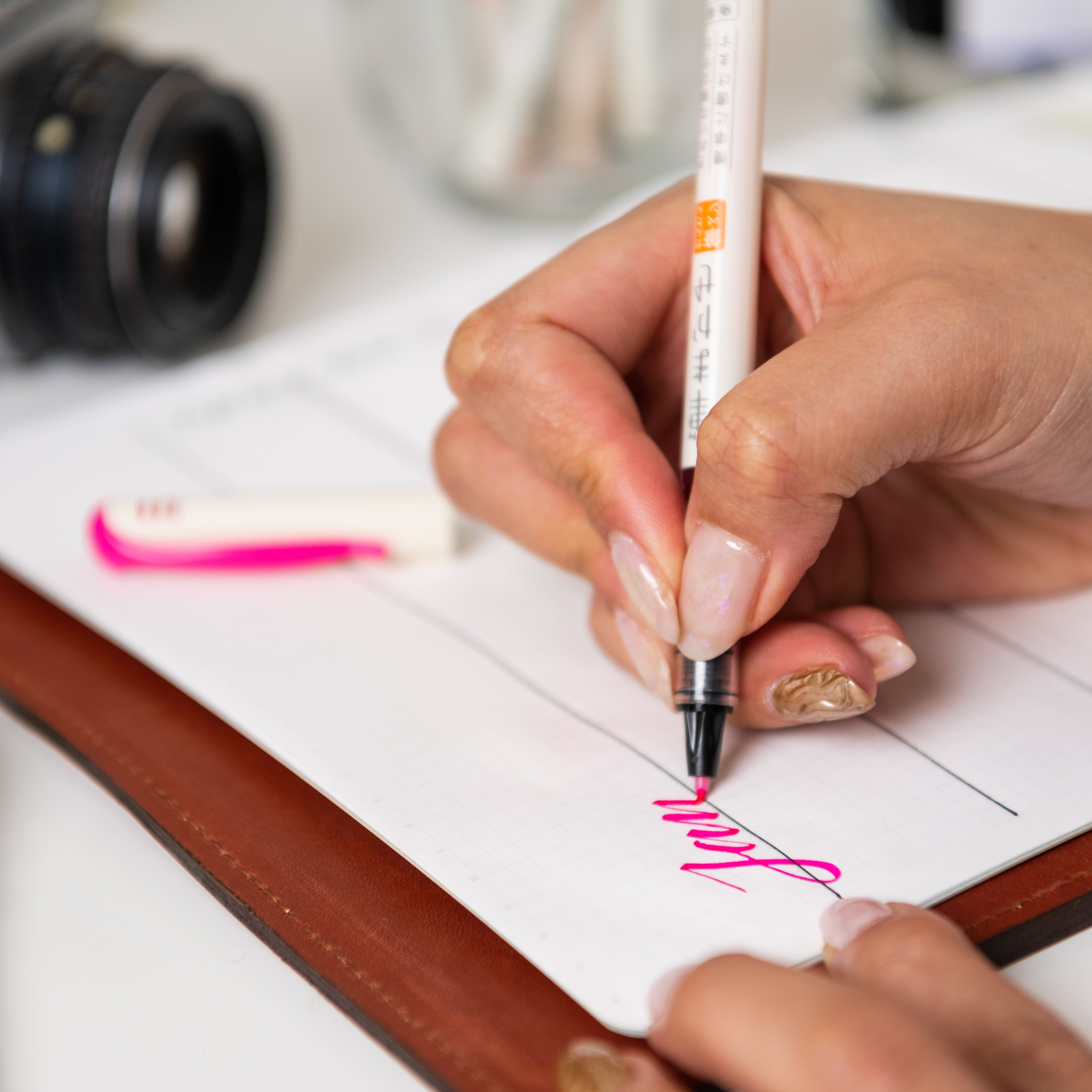 Vibrant pink ink from a Fude Makase Brush Pen used to write in a notebook, showcasing the variety of calligraphy tools available.