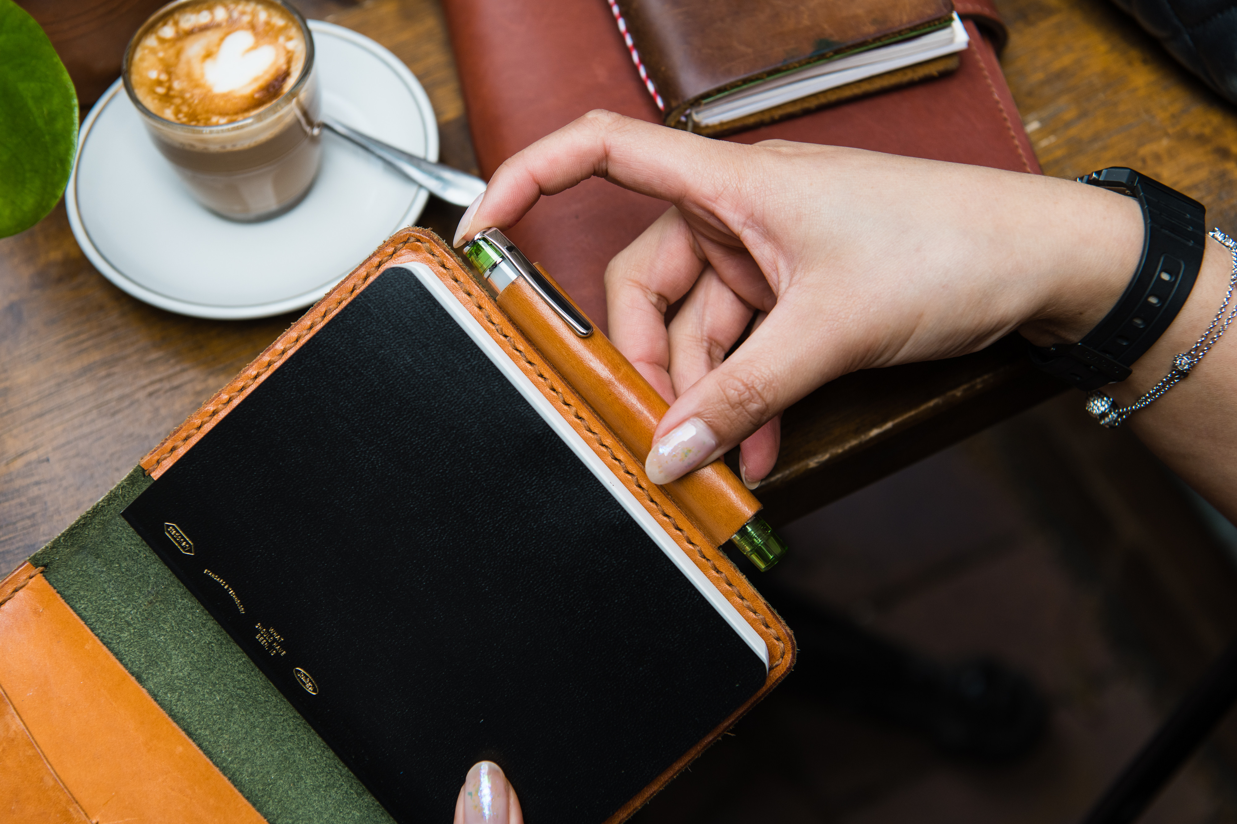 Pilot Prera Transparent fountain pen in pen holder of a leather-covered notepad in a cafe.