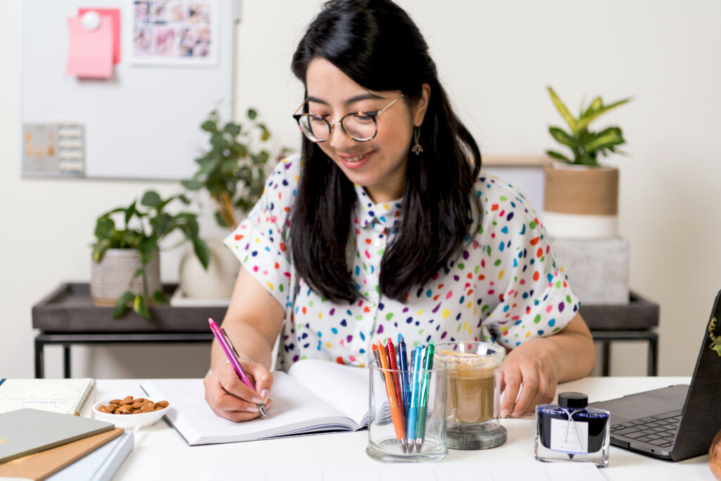 Person smiling using PILOT FriXion Point Knock to write.